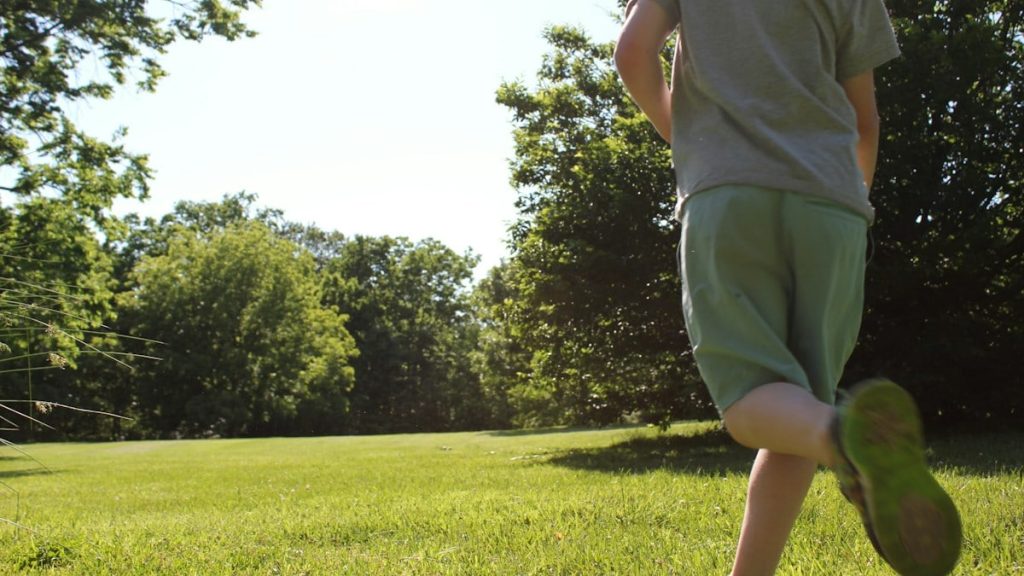 A boy runs across a green, sunny field