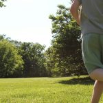 A boy runs across a green, sunny field