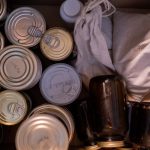 Top view of a box filled with canned goods, jars, and cloth sacks for storage.